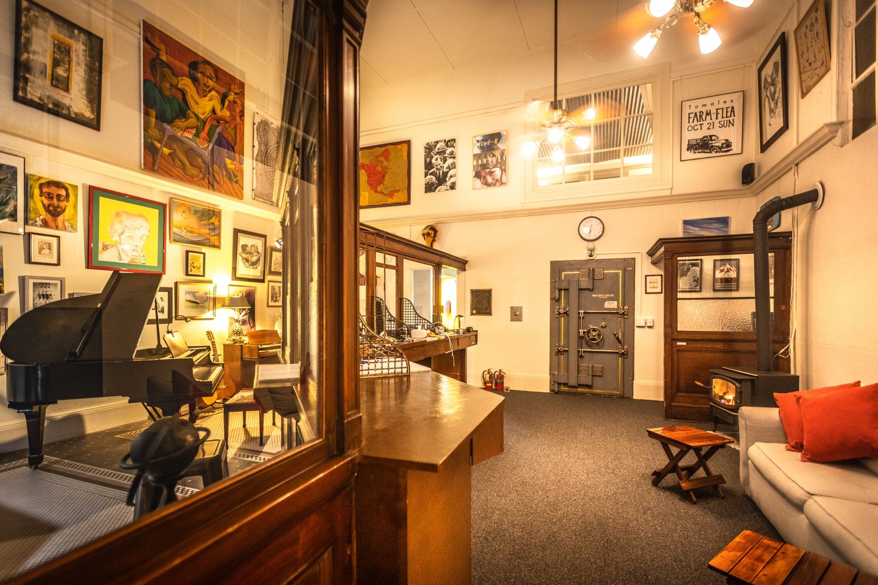 Main room at Not A Bank with piano, teller window, vault, gas stove, record player, Bluetooth speaker, and art