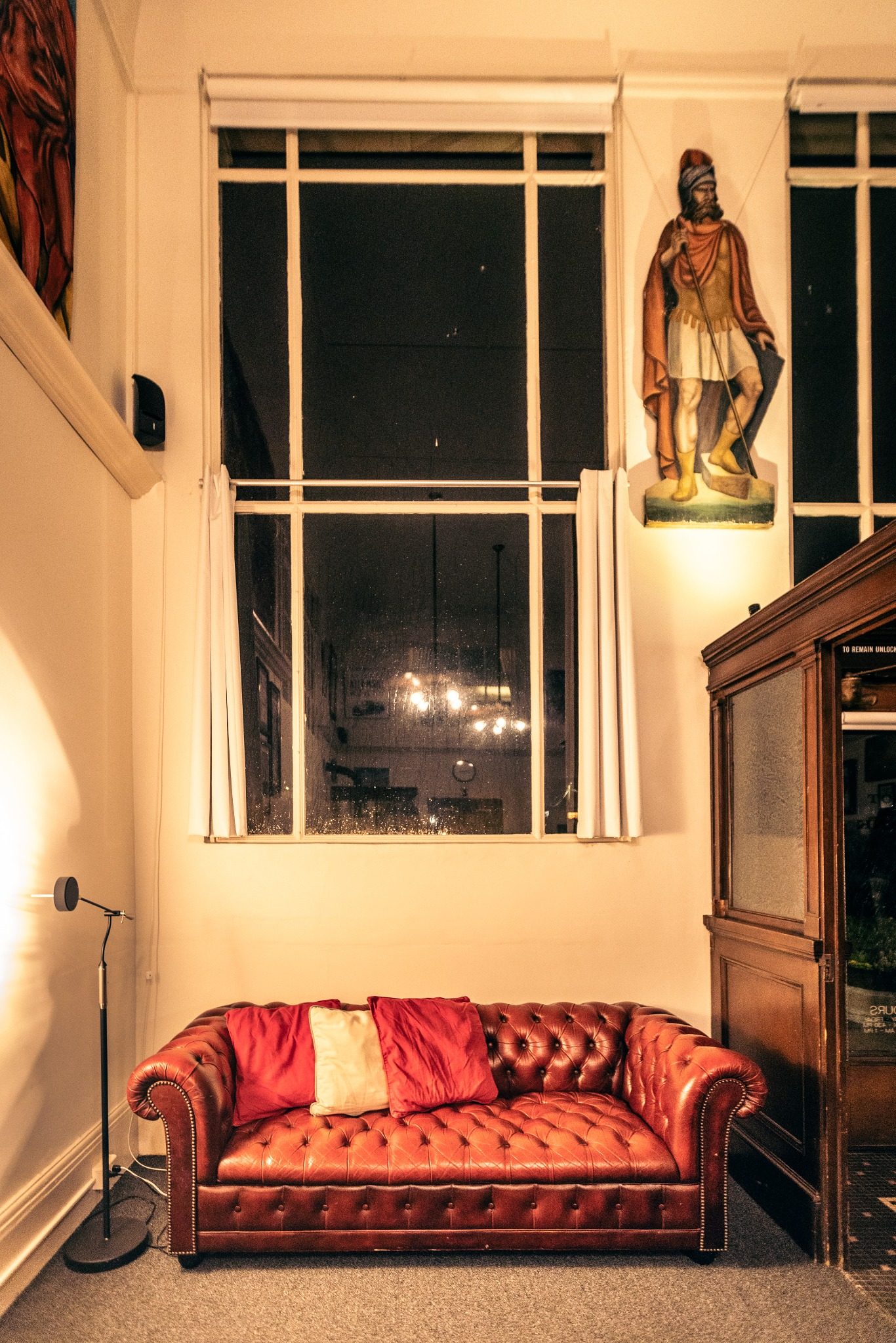 Red leather sofa beneath tall bank windows at Not A Bank